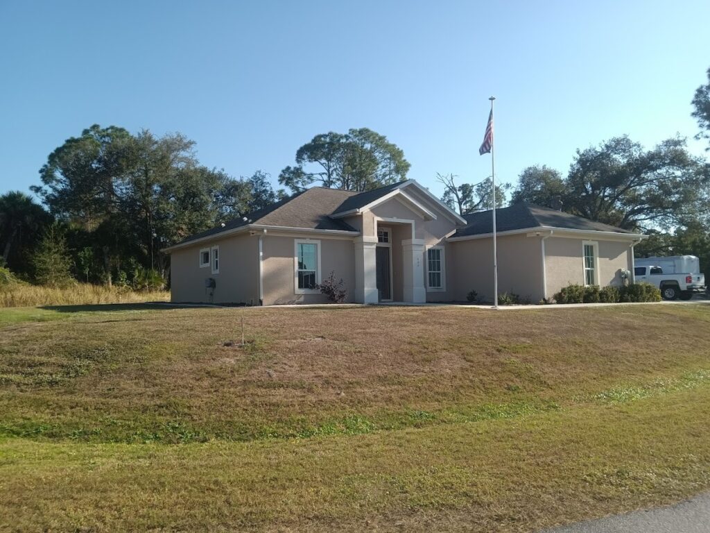 A single-story house with a front lawn and trees in the background.